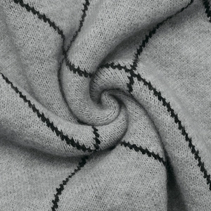 Close-up of soft grey knitted fabric with black check pattern for autumn sweaters
