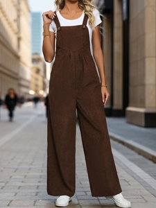 Close-up detail of dark brown corduroy overalls with brass metal buckles and V-stitch design