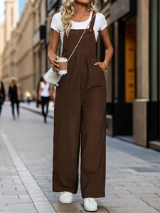 Detail shot of the corduroy texture and metal hardware on dark brown vintage overalls