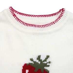 Detail of red contrast stitching on a white knit sweater with strawberry jacquard pattern