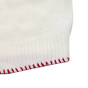 Close-up of white rib-knit sweater hem featuring decorative red hand-stitched details