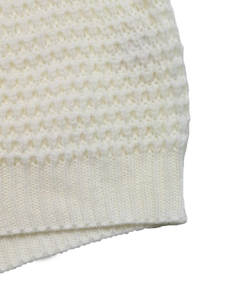 Macro detail of cream knit sweater showing honeycomb texture and ribbed cuffs