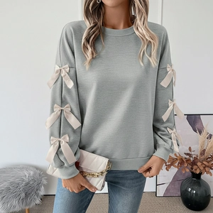 Sage green crewneck sweatshirt detail featuring white satin bows on the long sleeves