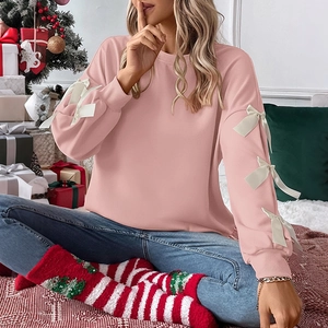 Detailed shot of pink long-sleeved sweatshirt featuring white bow accents on sleeves