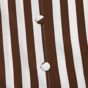 Détail d'une chemise rayée pour femme avec boutons contrastés et coutures fines