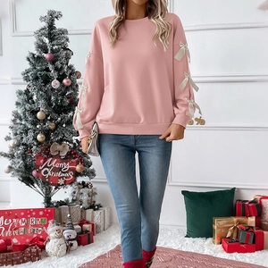 Detail of pink sweatshirt sleeves featuring off-white ribbon bow accents and soft fabric texture