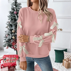 Close-up of pink crewneck sweatshirt featuring white silk bows on sleeves and knit texture