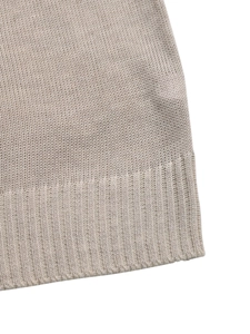 Close-up of beige knit fabric texture and ribbed cuff detail on the sleeve hem
