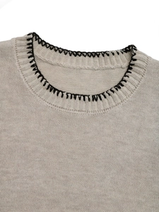Detailed close-up of crewneck knit vest with contrast hand-stitched black trim and ribbing