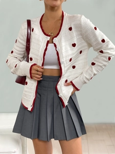 Close-up of white knit cardigan with red heart pattern and contrasting trim detail