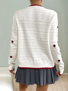 Detail of the back view of white knit cardigan with red hearts and wavy trim