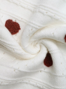Close-up of soft knit fabric texture with red heart jacquard and delicate openwork details