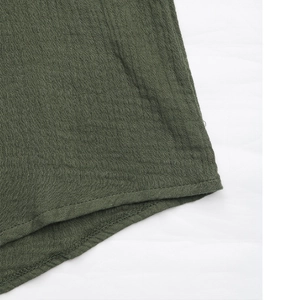 Dettaglio del tessuto di cotone testurizzato verde scuro con cuciture sull'orlo
