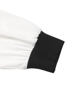 Detail of color-block dress showing white woven sleeve and black ribbed elastic cuff