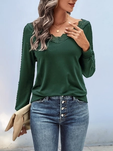 Close-up of elegant V-neckline with delicate lace trim on a dark green long sleeve top
