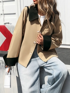 Detail of khaki button-up cardigan with black contrast collar and cuffs in street style