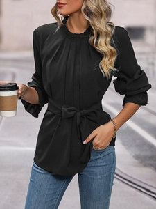 Detail of black long sleeve blouse with ruffled neckline, pleated chest, and waist tie belt
