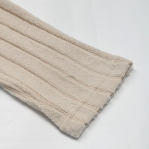 Dettaglio del polsino in maglia a coste beige con trama morbida e cuciture verticali