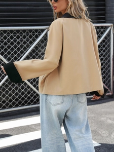 Street style view of a cropped khaki jacket with black contrast collar and blue wide-leg jeans