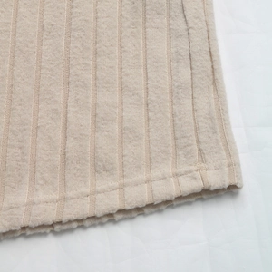 Primo piano del tessuto in maglia a costine beige con cuciture dettagliate e texture morbida