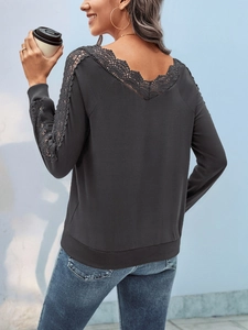 Detail of elegant black lace patchwork on the back of a V-neck long-sleeve women shirt