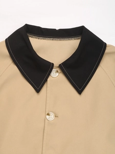 Detail of contrast lapel collar with white stitching and buttons on a beige cardigan