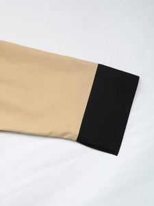Detailed view of khaki and black contrast stitching on the cuff of a short cardigan jacket
