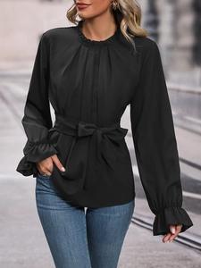 Detailed close-up of a black long-sleeve blouse with ruffle collar and bow tie waist