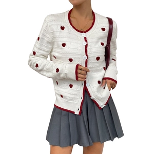 Women's white knit cardigan featuring red heart patterns and contrasting red ribbed trim