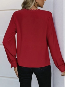 Detail of red long sleeve blouse featuring delicate lace trim on neckline and cuffs