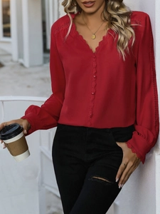 Detail of red chiffon top featuring a V-neckline with delicate lace trim and button accents
