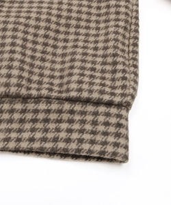 Detailed close-up of brown houndstooth fabric texture and stitching on the casual jacket