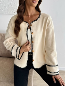 Detail of cream fleece cardigan with black whipstitch edges and amber buttons