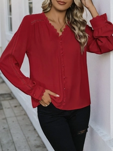 Detail of red long sleeve shirt featuring V-neck lace trim and elegant fabric covered buttons