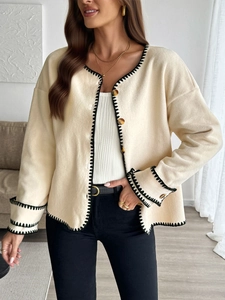 Detail of beige fleece cardigan featuring contrast black blanket stitching and tortoise buttons