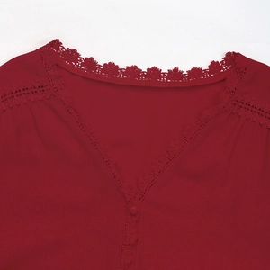 Detail of V-neckline with delicate burgundy lace trim and small button on the blouse