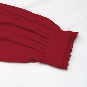 Detailed close-up of red chiffon blouse cuff with elegant lace trim and crochet stitching