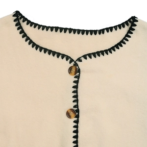 Detail of beige fleece cardigan with black contrast stitching and tortoiseshell buttons