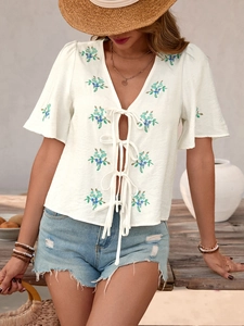 Detailed blue floral embroidery and tie-up bow closure on a white summer shirt