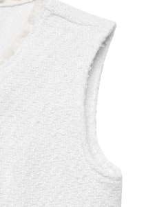 Detail of white tweed vest featuring woven texture and delicate fringe trim edges