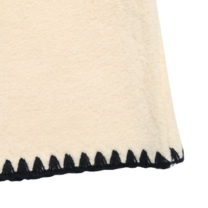 Detailed close-up of contrasting black blanket stitch on cream fleece jacket fabric