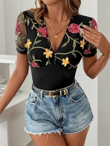 Detailansicht eines Sommer-Bodys mit V-Ausschnitt, Netzstoff und floraler Stickerei