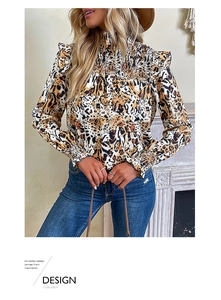 Detail of leopard print blouse featuring smocked high neck and ruffled shoulder accents