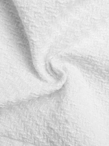 Detailed macro shot of premium white tweed fabric texture for women's elegant vest