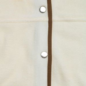 Detail of fleece cardigan showing brown fabric trim and silver metal snap buttons