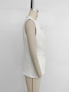 Detail of white tweed sleeveless vest with elegant golden buttons and rich woven texture