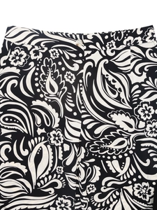 Detailed view of elastic waist and amber button on black paisley print trousers