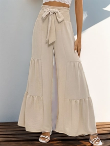 Detail of high waist apricot trousers featuring tiered ruffle layers and tie-waist bow design