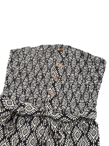 Detail of bohemian print strapless romper featuring wood-style buttons and smocked bodice