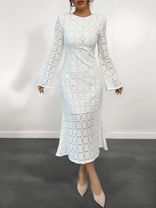 Dettaglio di un vestito in pizzo bianco con motivi traforati geometrici e maniche svasate